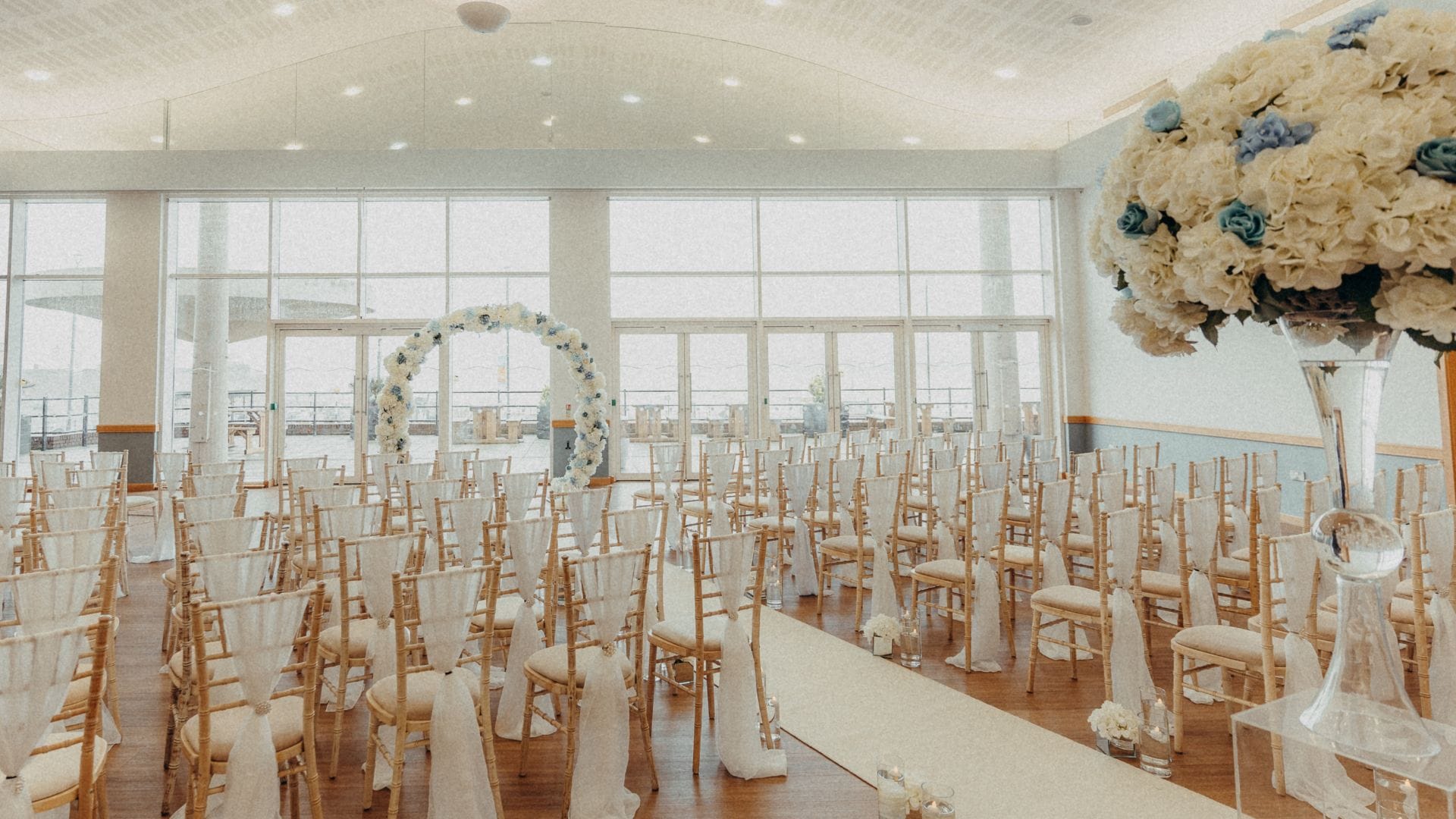 Winter Garden Suite set for a wedding ceremony. Chiavari chairs with white linens and white/blue florals.