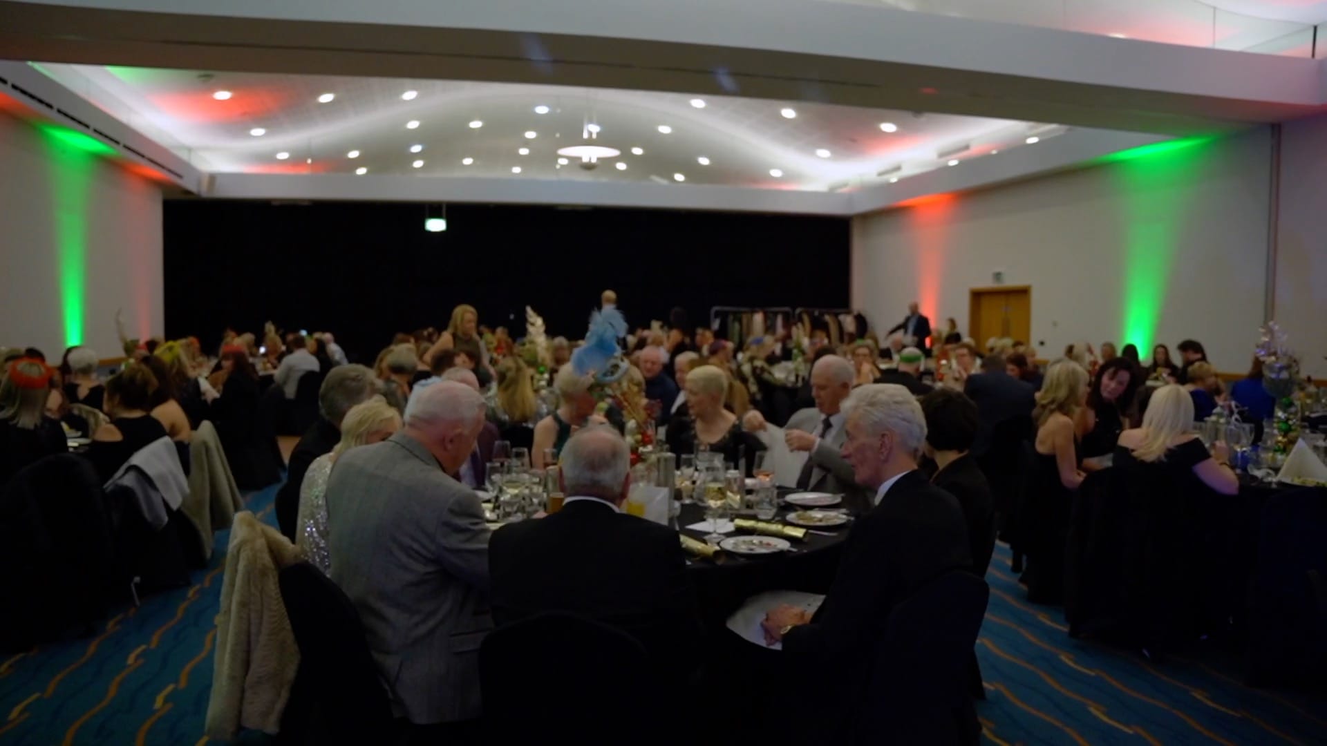 Conference Suite set with round tables and full of people celebrating at a Christmas Party.